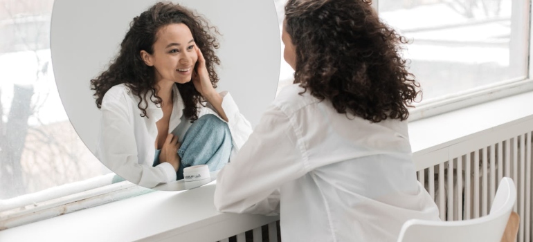 The picture of a girl looking herself in the mirror presents Balancing Self-Care While Supporting an Addicted Loved One