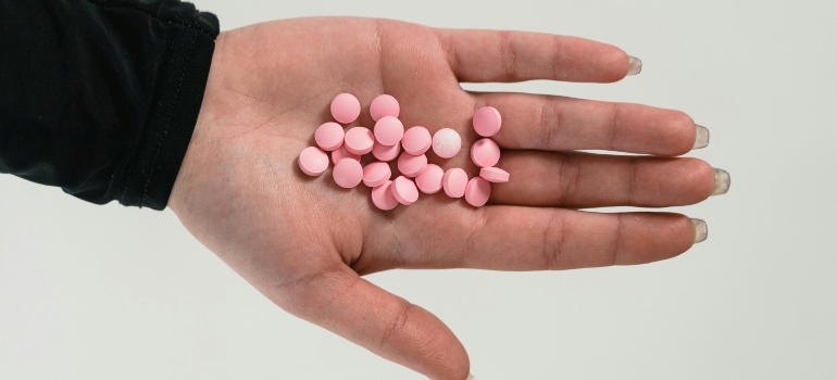 Pink medicine tablets on women's palm.