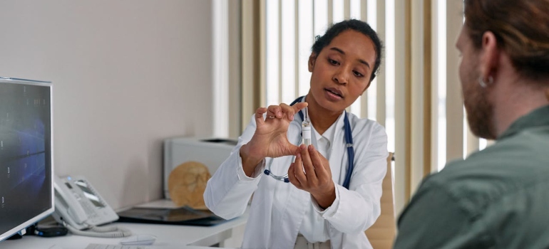 A female doctor showing a medication to her patient.