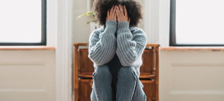 Woman sitting down and covering her face.