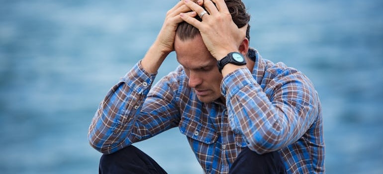 Man sitting down and holding his head.