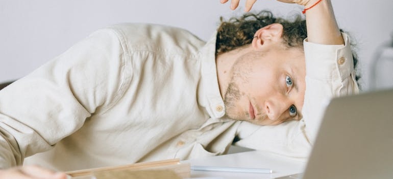 Man lying on the table and looking at a laptop.