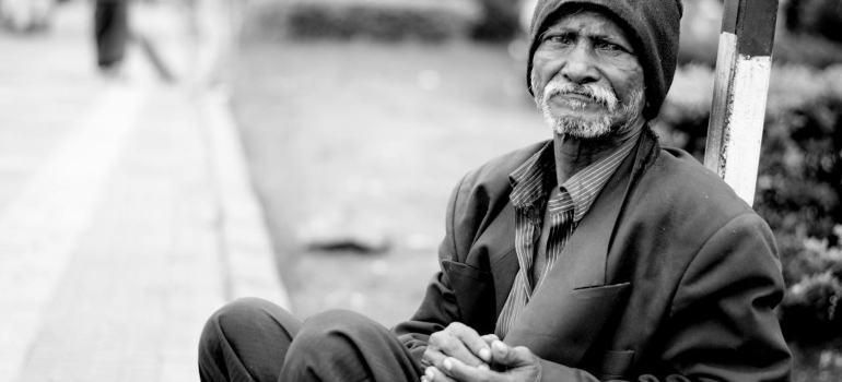 A poor man begging on the street grayscale