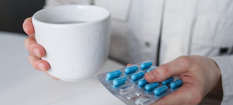 Doctor holding a mug and a blister of pills.