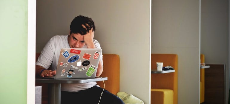 Man sitting at a booth and looking at a laptop.