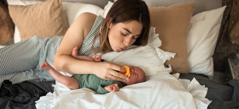 Woman putting a pacifier in her baby's mouth.