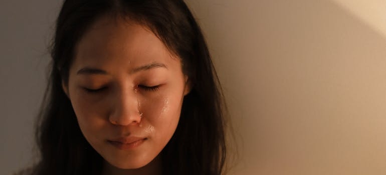 Woman crying while leaning against the wall.