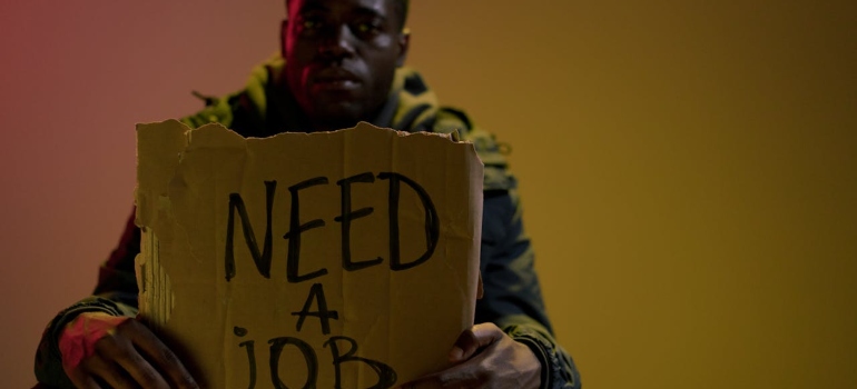 A man holding "need a job" sign