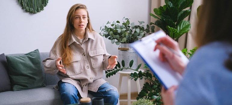 Therapist talking to a patient and writing on a clipboard.