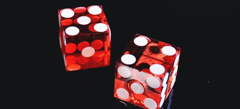 Two red dice on a black surface.