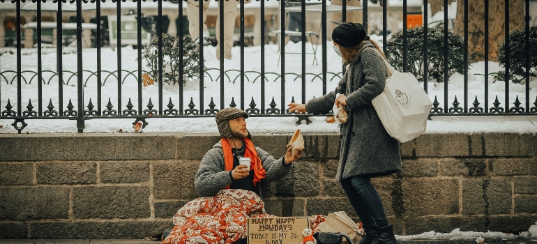 A woman giving money to a homeless person