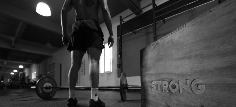 A man standing beside barbell