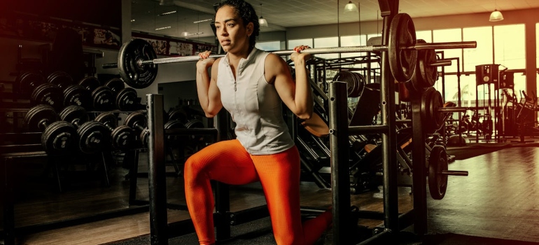 Woman kneeling with barbell on shoulders