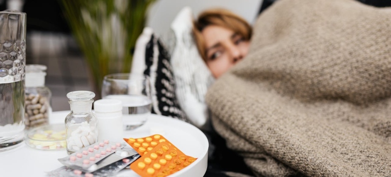 a girl in bed next to a desk with lots of drugs