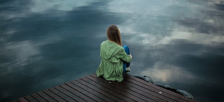 Woman sitting on the bridge by the water.