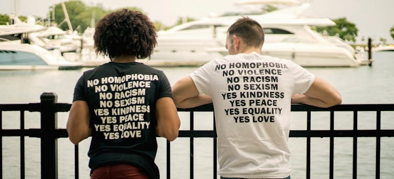 Two men standing near a bridge in inclusive t-shirts.