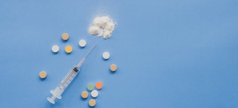 Syringe surrounded by tablets.