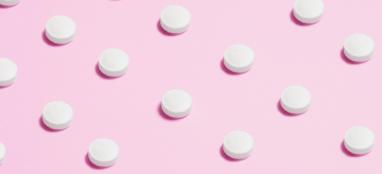 White pills on a pink background