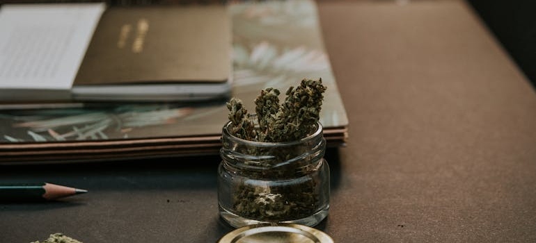 Marijuana in a jar on a wooden table.