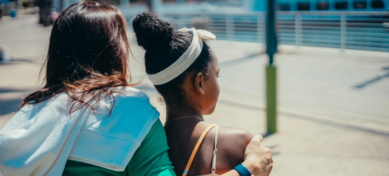 A woman hugging a girl with a white hair band.