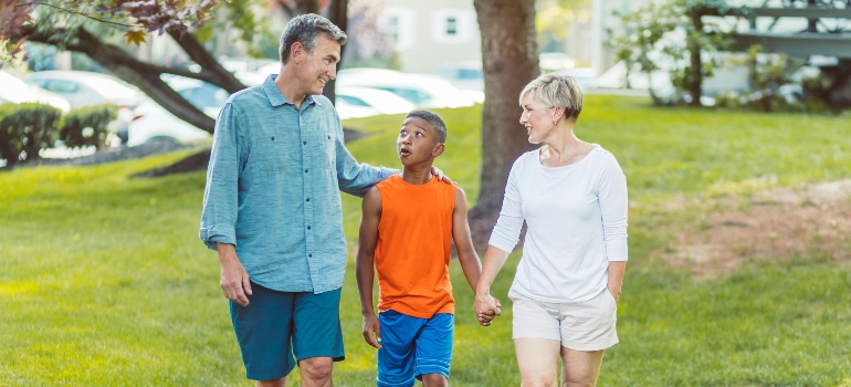 Parents are talking to a child while walking outside at the park.