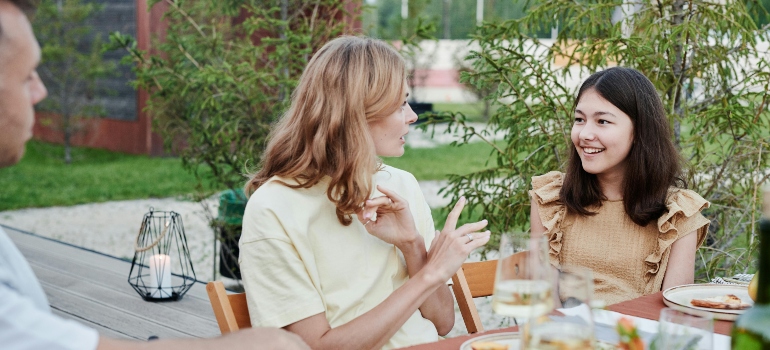 Two people are sitting at the table and talking to a girl about how to educate kids on the dangers of alcohol.