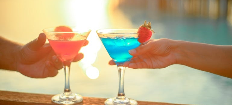 Two people drinking mocktails near a pool.