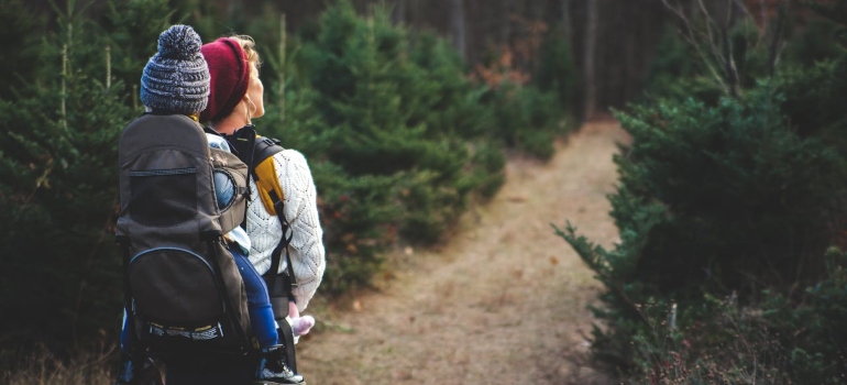 a woman carrying a child through the forest