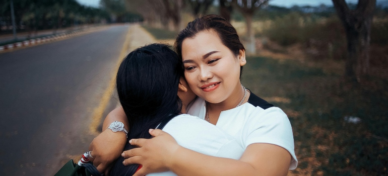 Two women are hugging in the street.