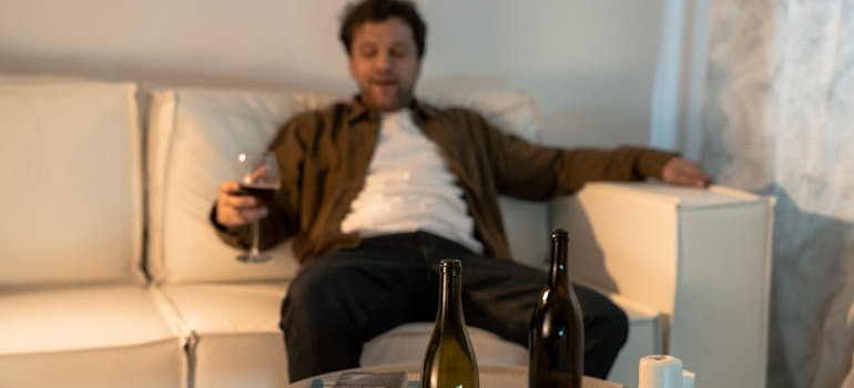 Man sitting on a couch and drinking wine.