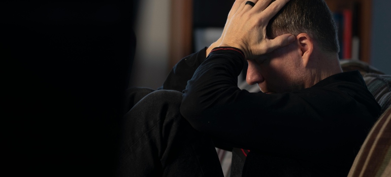 A man sitting on the chair, holding his head and thinking about marijuana and panic attacks.