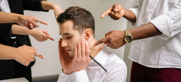 People pointing their fingers at a stressed man at work.