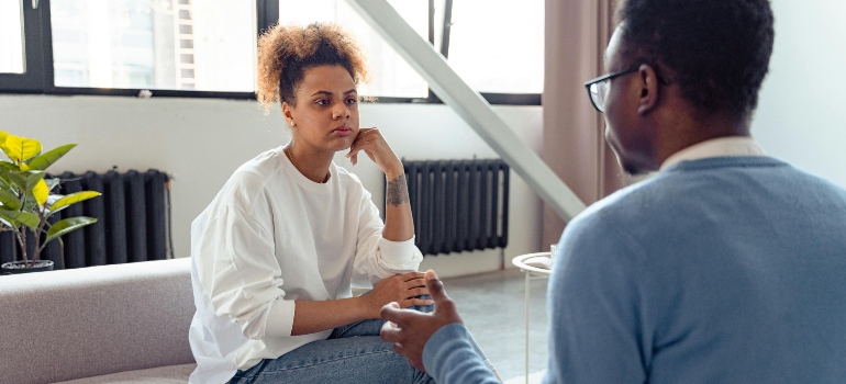 A woman is sitting on the couch and talking to a therapist.