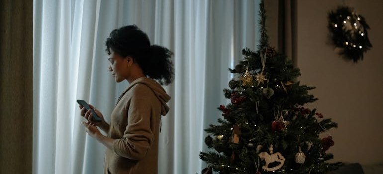 A woman standing near a Christmas tree and thinking about feeling depressed at Christmas.