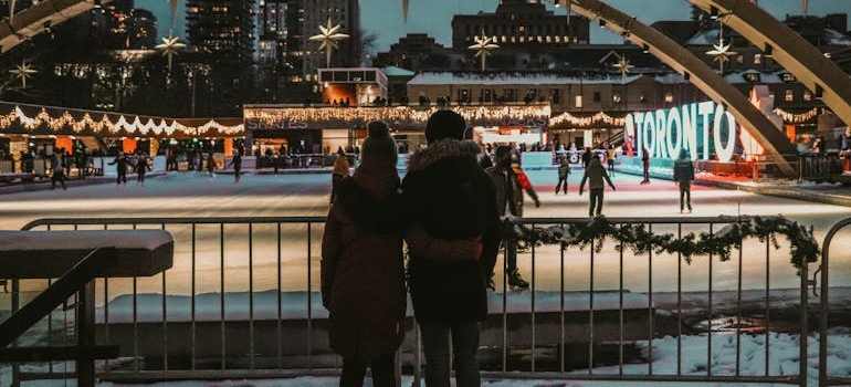 Two people hugging in front of an ice rink.