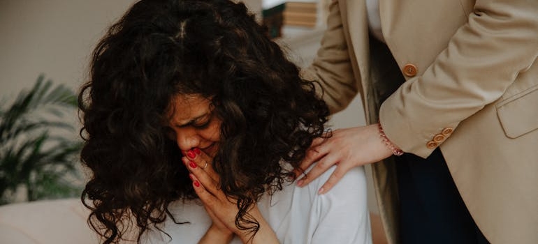 Woman crying and another woman comforting her.