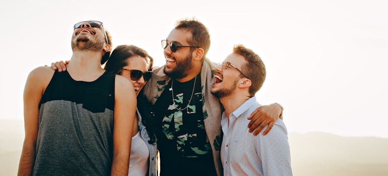 Group of four friends laughing and hugging.